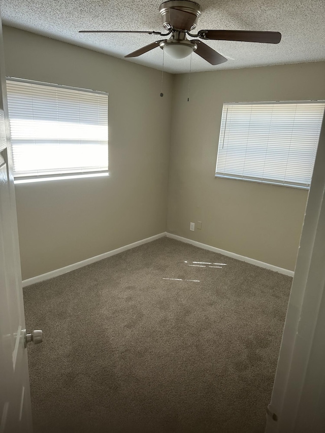 empty room with carpet, baseboards, and a textured ceiling