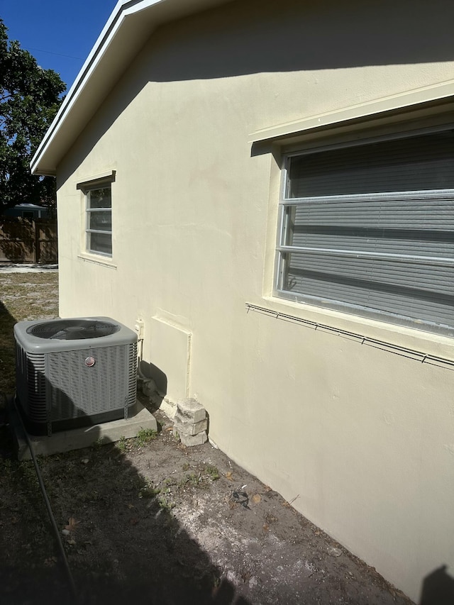 view of side of home featuring central AC unit and stucco siding