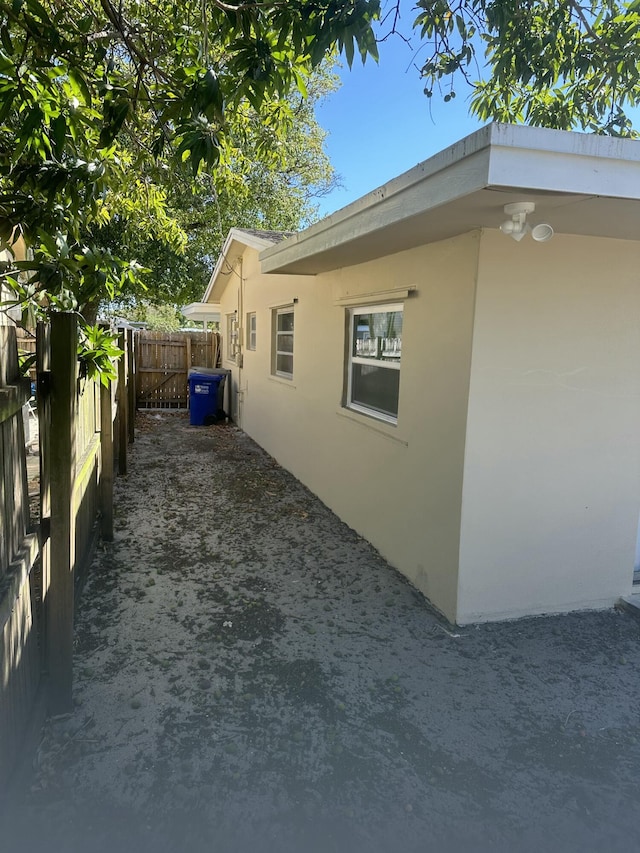 view of side of property with stucco siding and fence