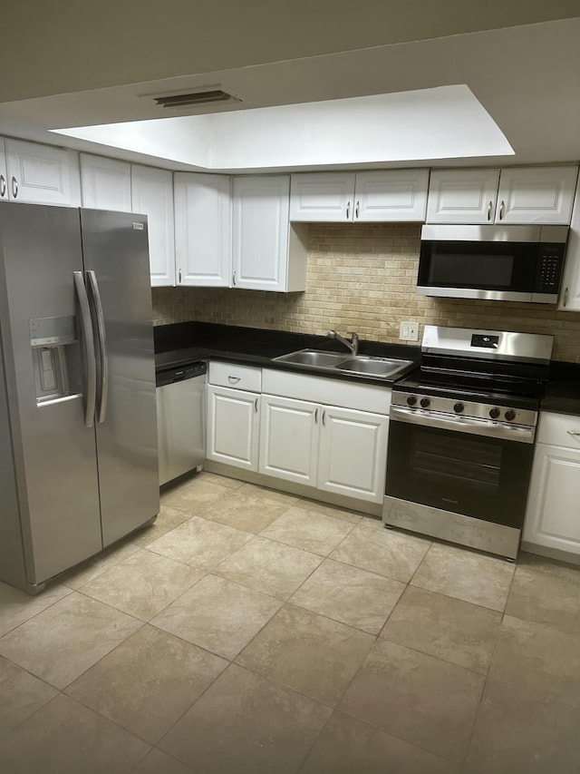 kitchen with a sink, tasteful backsplash, appliances with stainless steel finishes, and white cabinetry