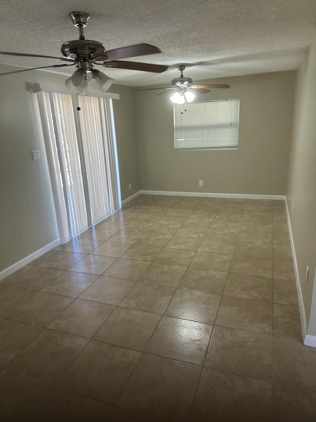 tiled empty room featuring baseboards and a textured ceiling