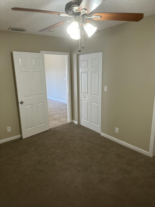 spare room featuring visible vents, a textured ceiling, carpet flooring, baseboards, and ceiling fan