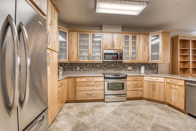 kitchen with tasteful backsplash, light stone countertops, light brown cabinets, and appliances with stainless steel finishes