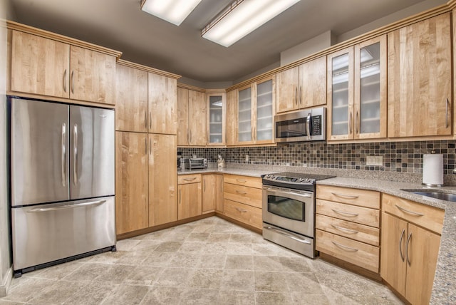 kitchen with sink, light stone counters, light brown cabinets, stainless steel appliances, and backsplash