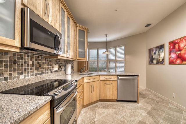 kitchen featuring appliances with stainless steel finishes, tasteful backsplash, sink, hanging light fixtures, and light stone countertops