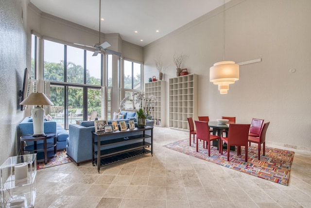 interior space with ceiling fan, a high ceiling, and crown molding