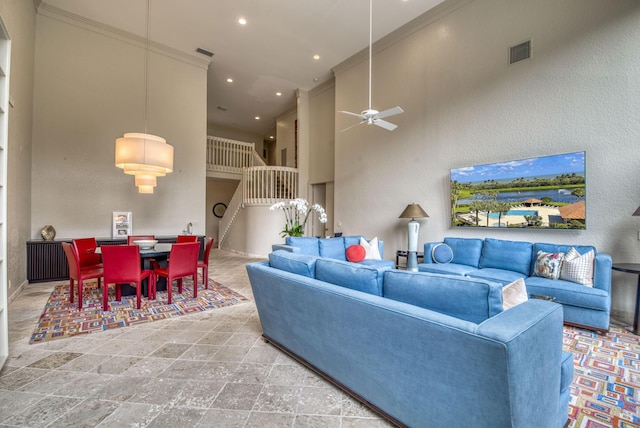 living room featuring ceiling fan, ornamental molding, and a towering ceiling