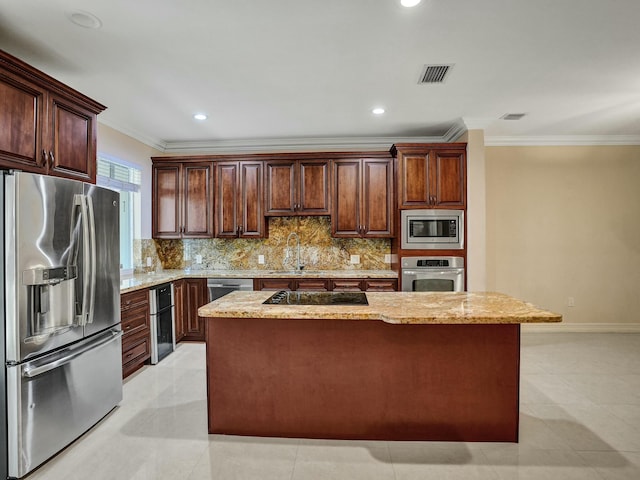 kitchen featuring sink, crown molding, stainless steel appliances, light stone counters, and a kitchen island