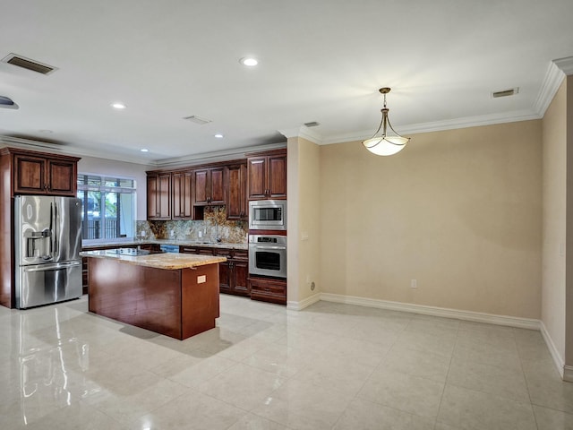 kitchen featuring crown molding, hanging light fixtures, appliances with stainless steel finishes, a kitchen island, and light stone countertops