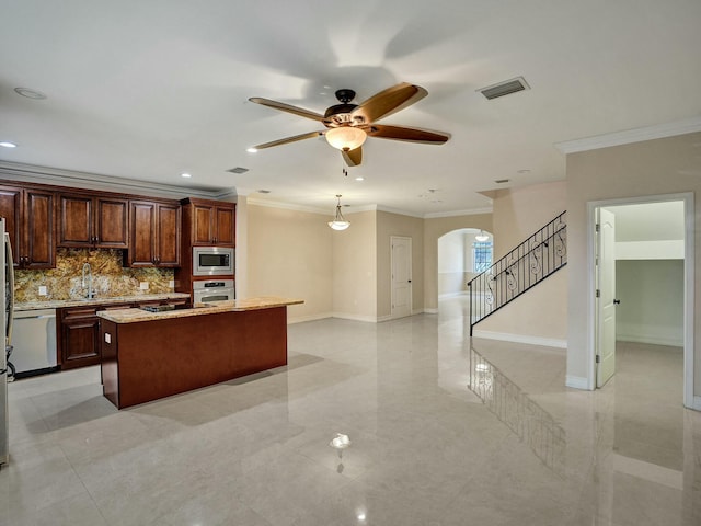 kitchen featuring sink, crown molding, stainless steel appliances, a kitchen island with sink, and backsplash