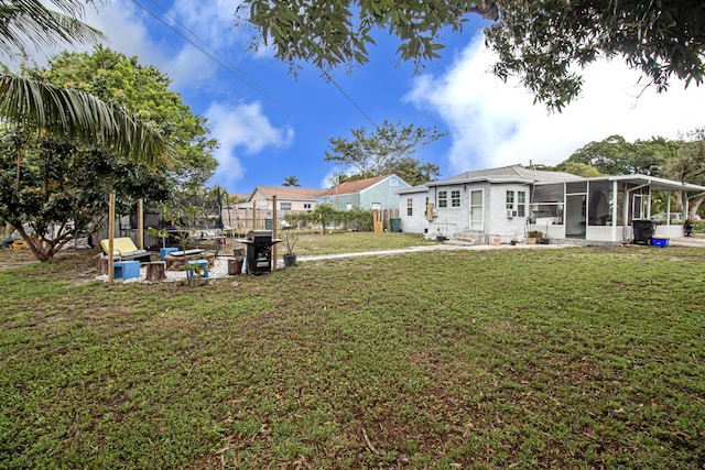 view of yard with a trampoline and a sunroom