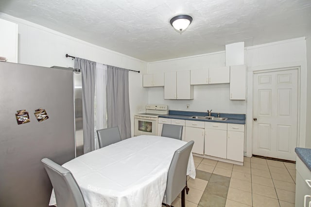 kitchen with light tile patterned flooring, white electric stove, white cabinetry, sink, and stainless steel fridge