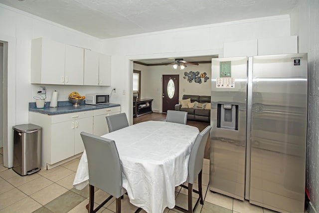 tiled dining space featuring ornamental molding and ceiling fan