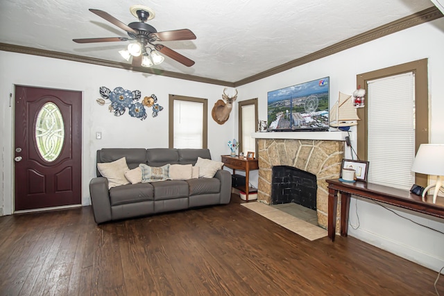 living room featuring ceiling fan, a fireplace, wood-type flooring, ornamental molding, and a textured ceiling