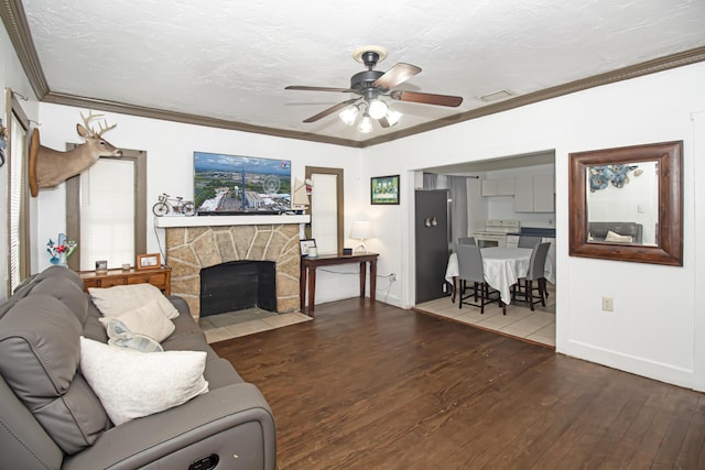 living room with crown molding, a textured ceiling, dark hardwood / wood-style flooring, ceiling fan, and a fireplace