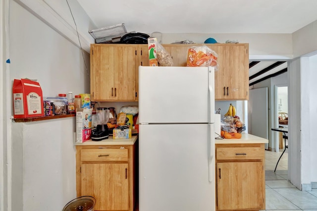 kitchen with light brown cabinets, light countertops, light tile patterned floors, and freestanding refrigerator