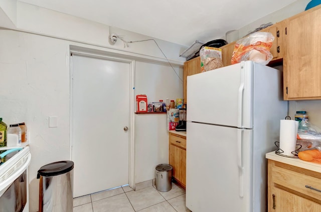 kitchen with light countertops, light tile patterned floors, and freestanding refrigerator