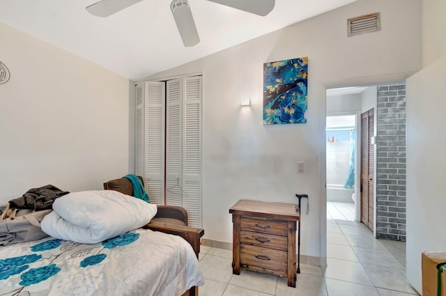 bedroom featuring vaulted ceiling, light tile patterned flooring, connected bathroom, visible vents, and a closet