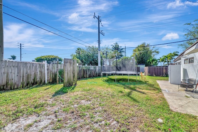 view of yard with a trampoline, a fenced backyard, and a patio