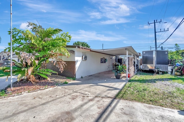 view of front of house with an attached carport, driveway, and stucco siding