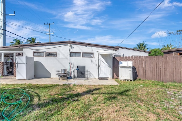 back of house featuring a lawn, stucco siding, fence, and a patio area