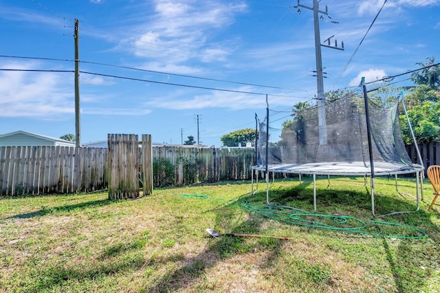 view of yard with a trampoline and fence