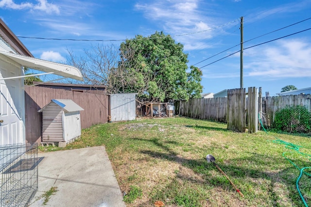view of yard with a storage unit, a fenced backyard, an outbuilding, and a patio
