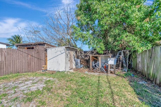 view of yard featuring an outbuilding, a fenced backyard, and exterior structure