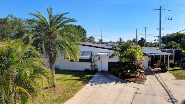 view of front facade featuring stucco siding, a front lawn, and concrete driveway