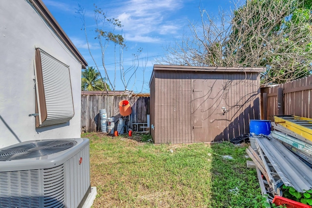 view of yard with an outbuilding, central AC unit, a fenced backyard, and a storage shed