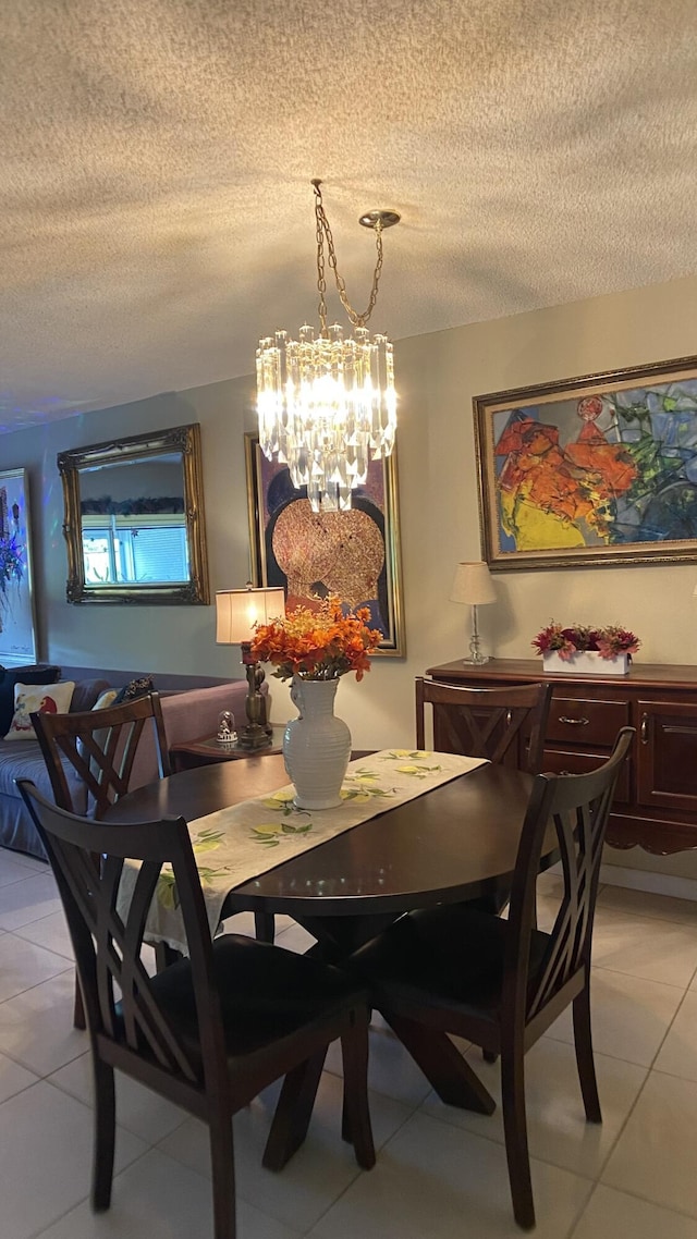 dining space with a notable chandelier, a textured ceiling, and light tile patterned flooring