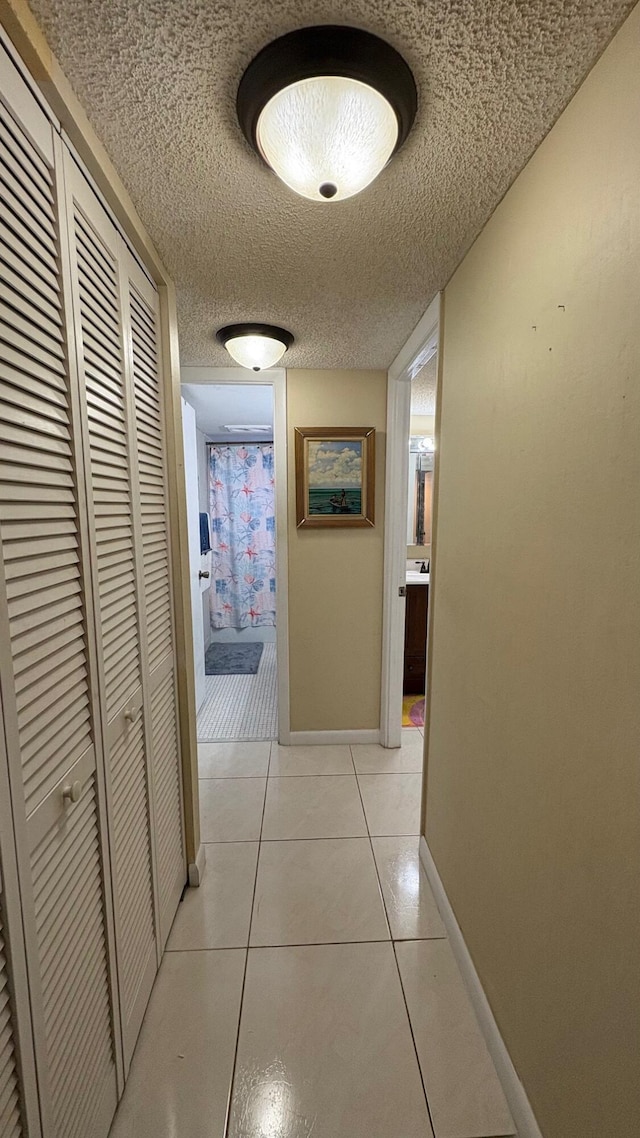 corridor with a textured ceiling and light tile patterned floors