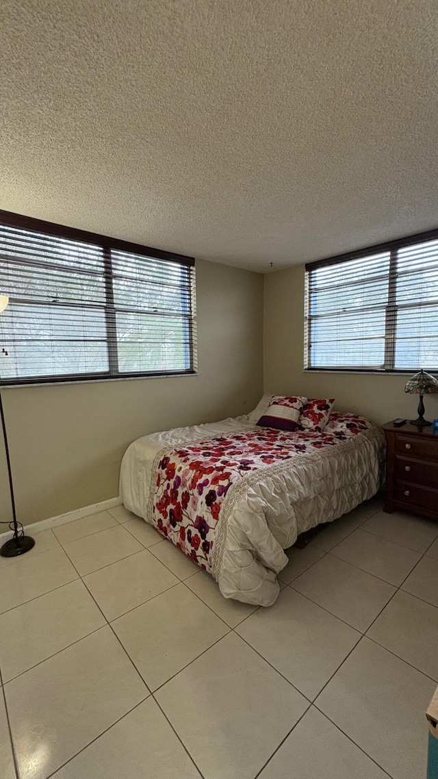 bedroom featuring tile patterned flooring, a textured ceiling, and multiple windows