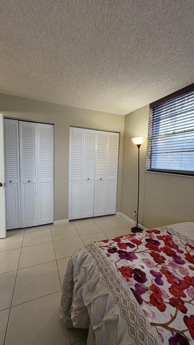 unfurnished bedroom featuring two closets, a textured ceiling, and light tile patterned floors