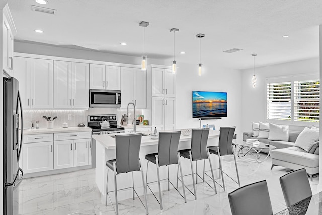 kitchen with white cabinets, pendant lighting, and appliances with stainless steel finishes