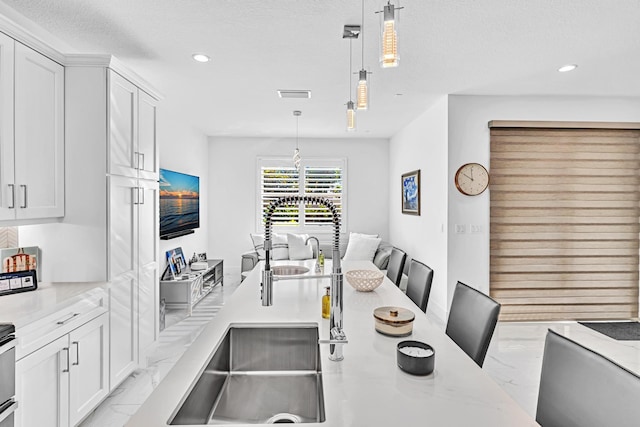 kitchen with decorative light fixtures, white cabinetry, and light stone countertops