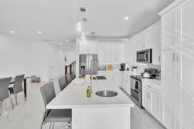 kitchen with a center island with sink, a kitchen bar, hanging light fixtures, and stainless steel appliances