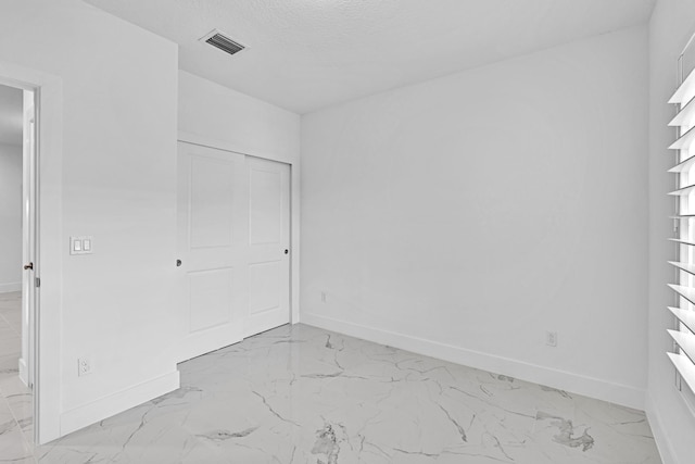 unfurnished bedroom featuring a textured ceiling and a closet