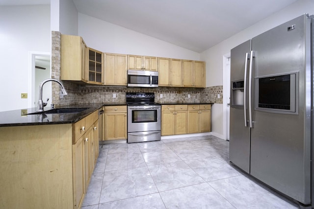 kitchen with kitchen peninsula, appliances with stainless steel finishes, sink, decorative backsplash, and lofted ceiling