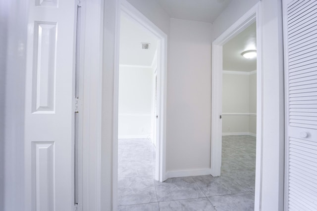 corridor featuring light tile patterned floors and ornamental molding