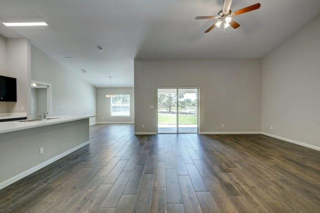 unfurnished living room with sink, ceiling fan with notable chandelier, and vaulted ceiling