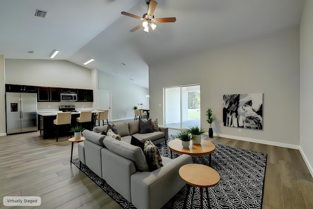 living room with ceiling fan, high vaulted ceiling, and light hardwood / wood-style flooring