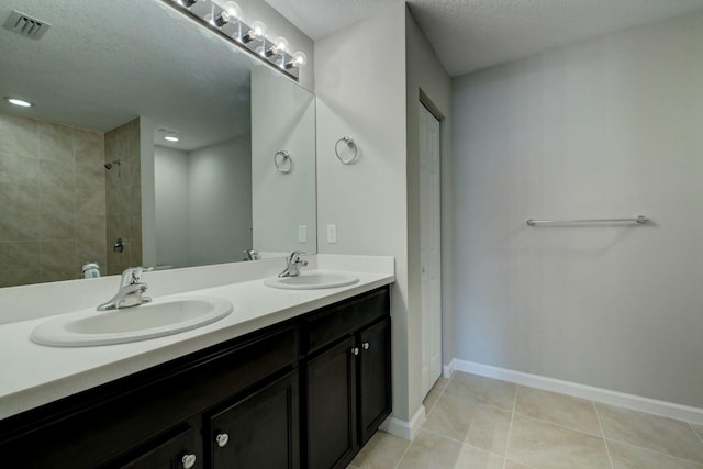 bathroom with vanity, tile patterned flooring, a textured ceiling, and a shower