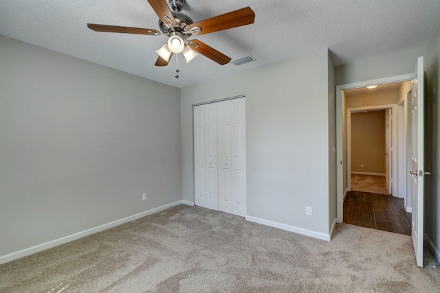 unfurnished bedroom with light colored carpet, a textured ceiling, ceiling fan, and a closet