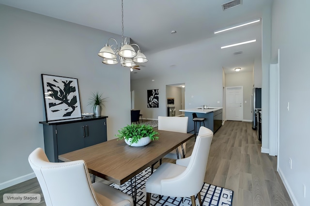 dining room featuring an inviting chandelier, sink, and light wood-type flooring