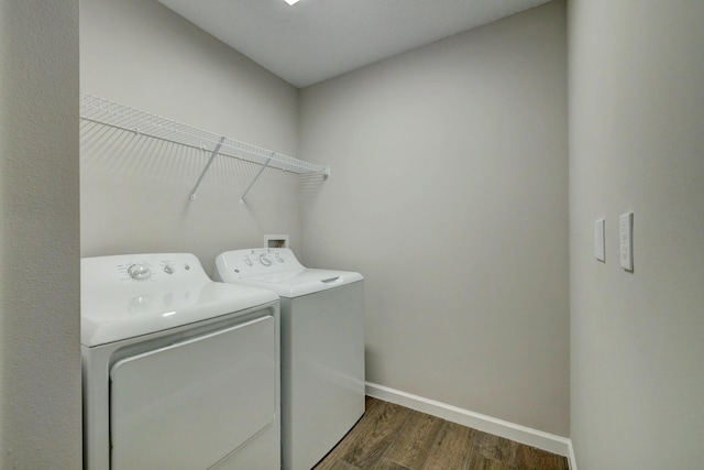 washroom with washing machine and clothes dryer and dark hardwood / wood-style floors