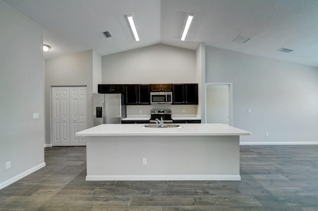 kitchen with appliances with stainless steel finishes, a kitchen island with sink, sink, and high vaulted ceiling