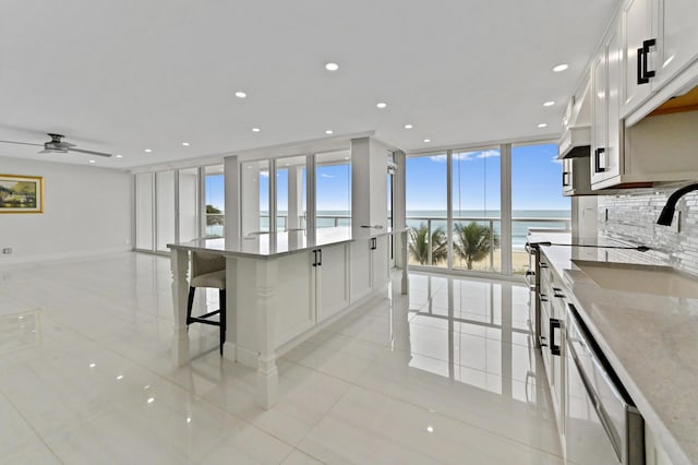 kitchen featuring light tile patterned flooring, a water view, dishwasher, and white cabinets