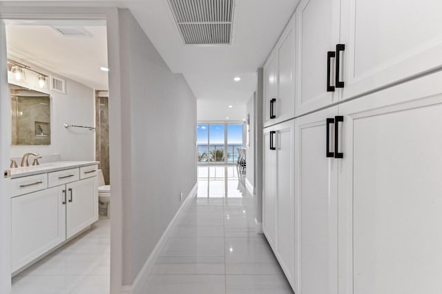 corridor with sink, floor to ceiling windows, and light tile patterned flooring