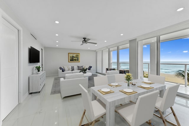 dining room with ceiling fan, floor to ceiling windows, and a beach view